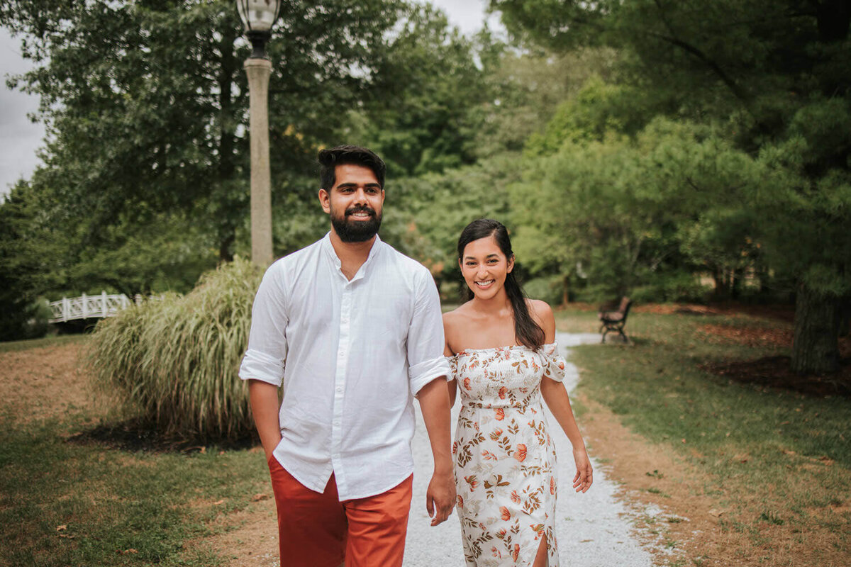A couple enjoys a serene stroll on a tree-lined path in Hamilton Square, NJ, radiating happiness and love.