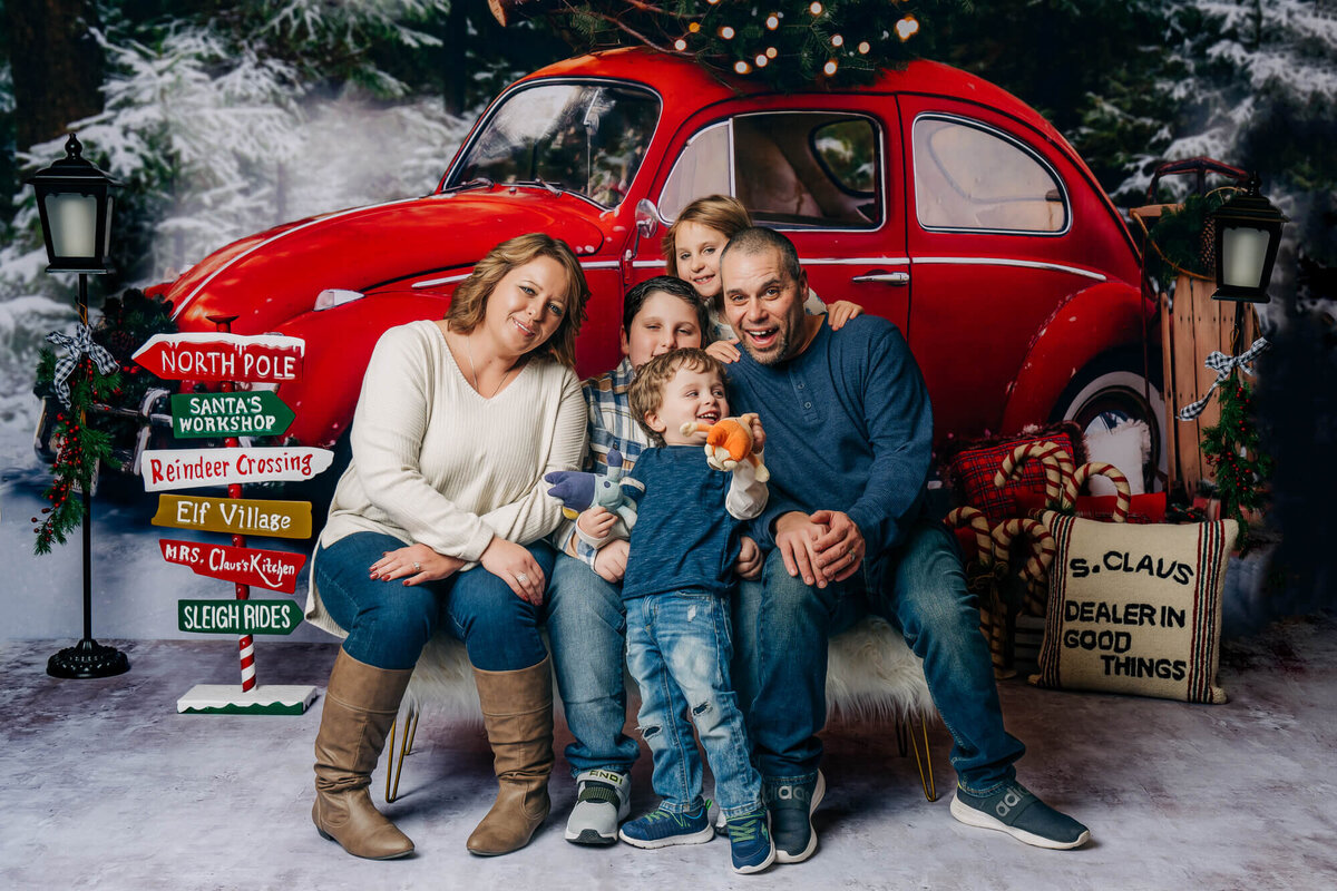 Family poses in front of red vintage VW bug in holiday Prescott family photos