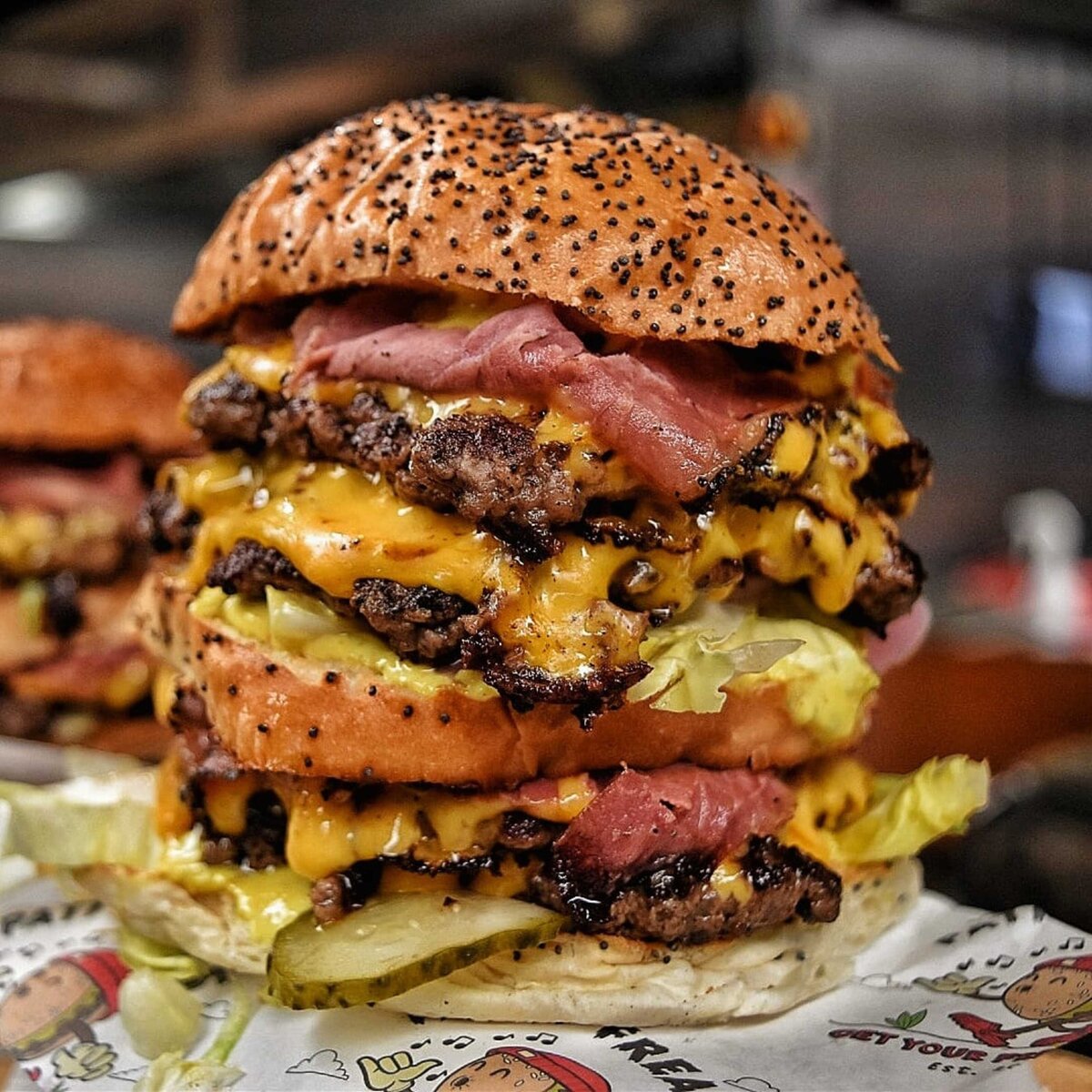 Huge triple stacked burger with bacon, cheese, gherkins and lettuce