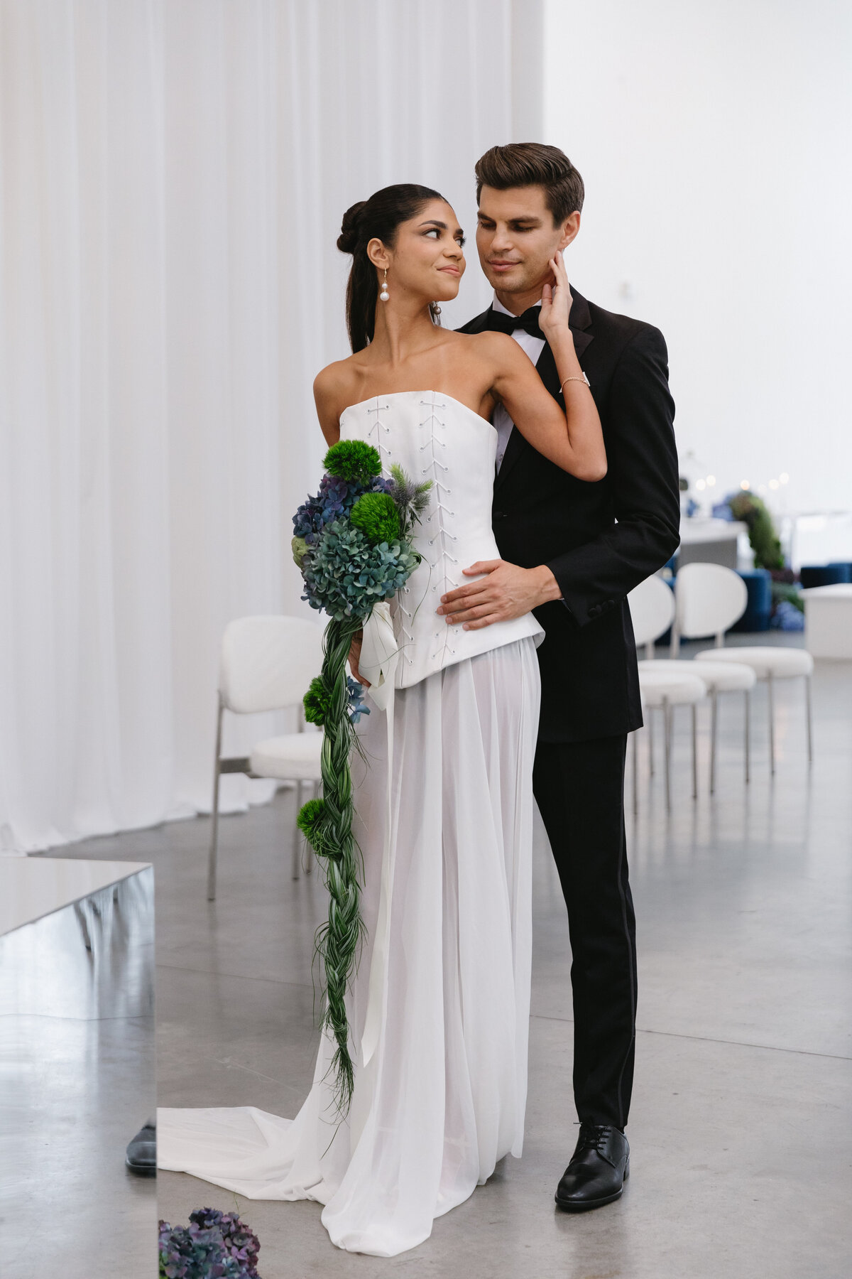 Close-up of sculptural blue and green wedding florals with textured greenery at a modern New York City editorial wedding shoot.
