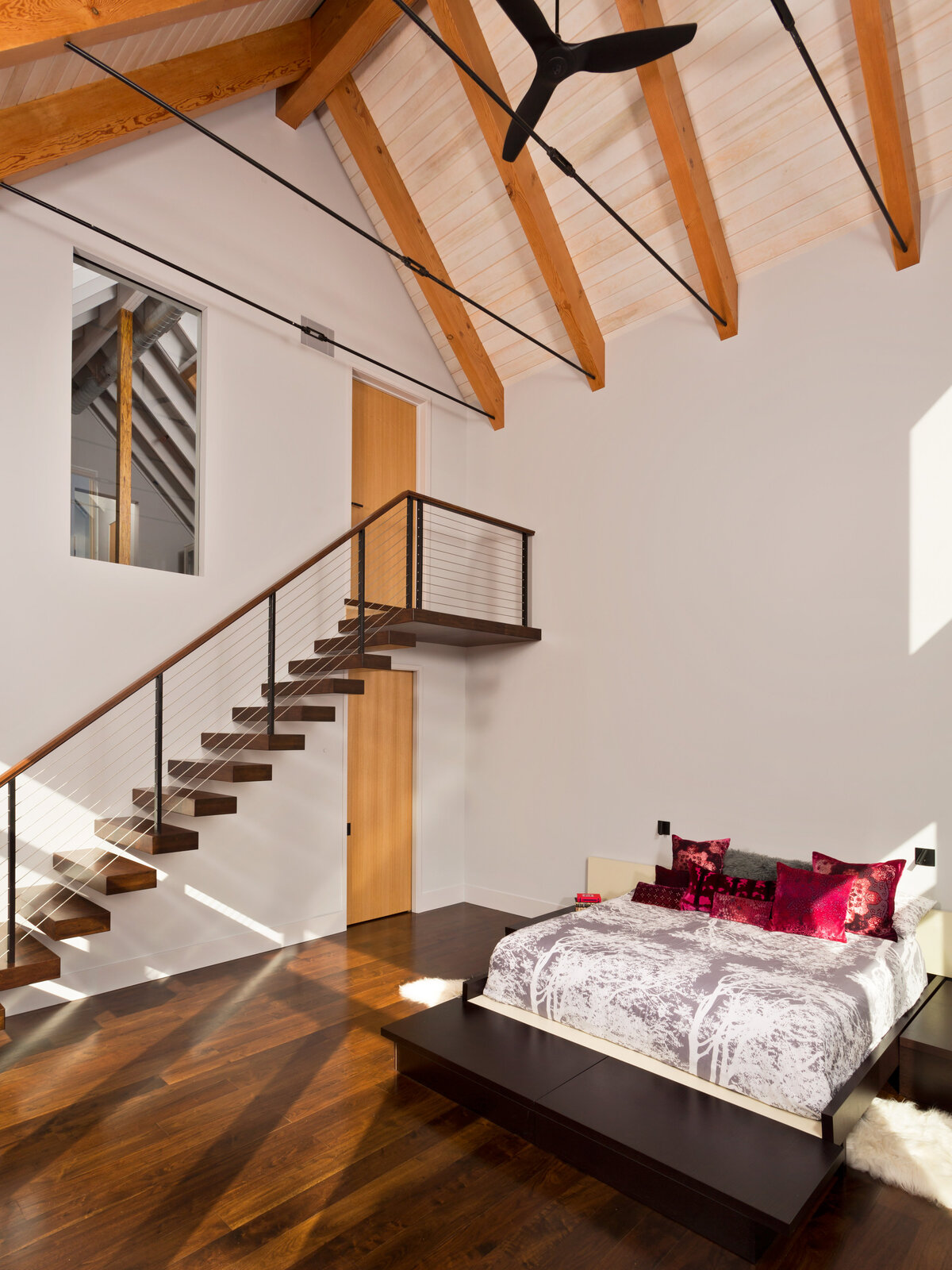 white bedroom with wood accents and large staircase