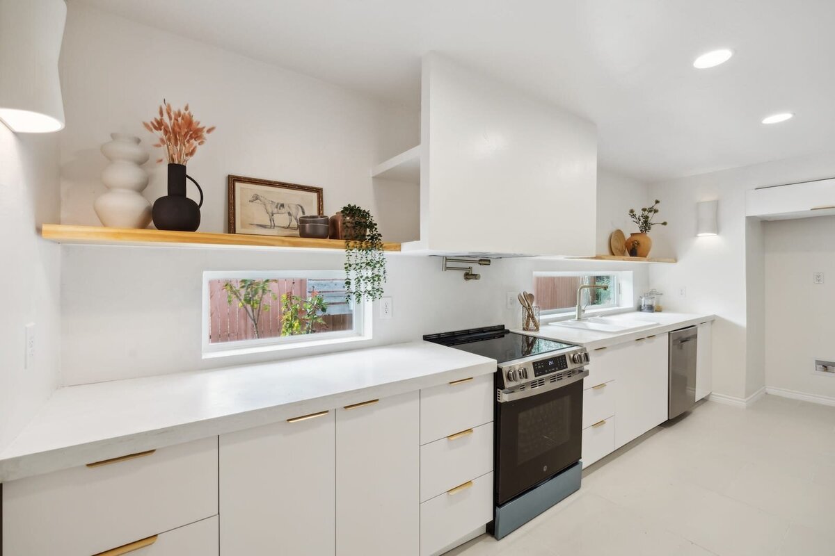 Sleek modern kitchen at 3120 Chapel Downs Dr Dallas TX showcasing white countertops, open wood shelving, and natural light — presented by Haven Realty Group.