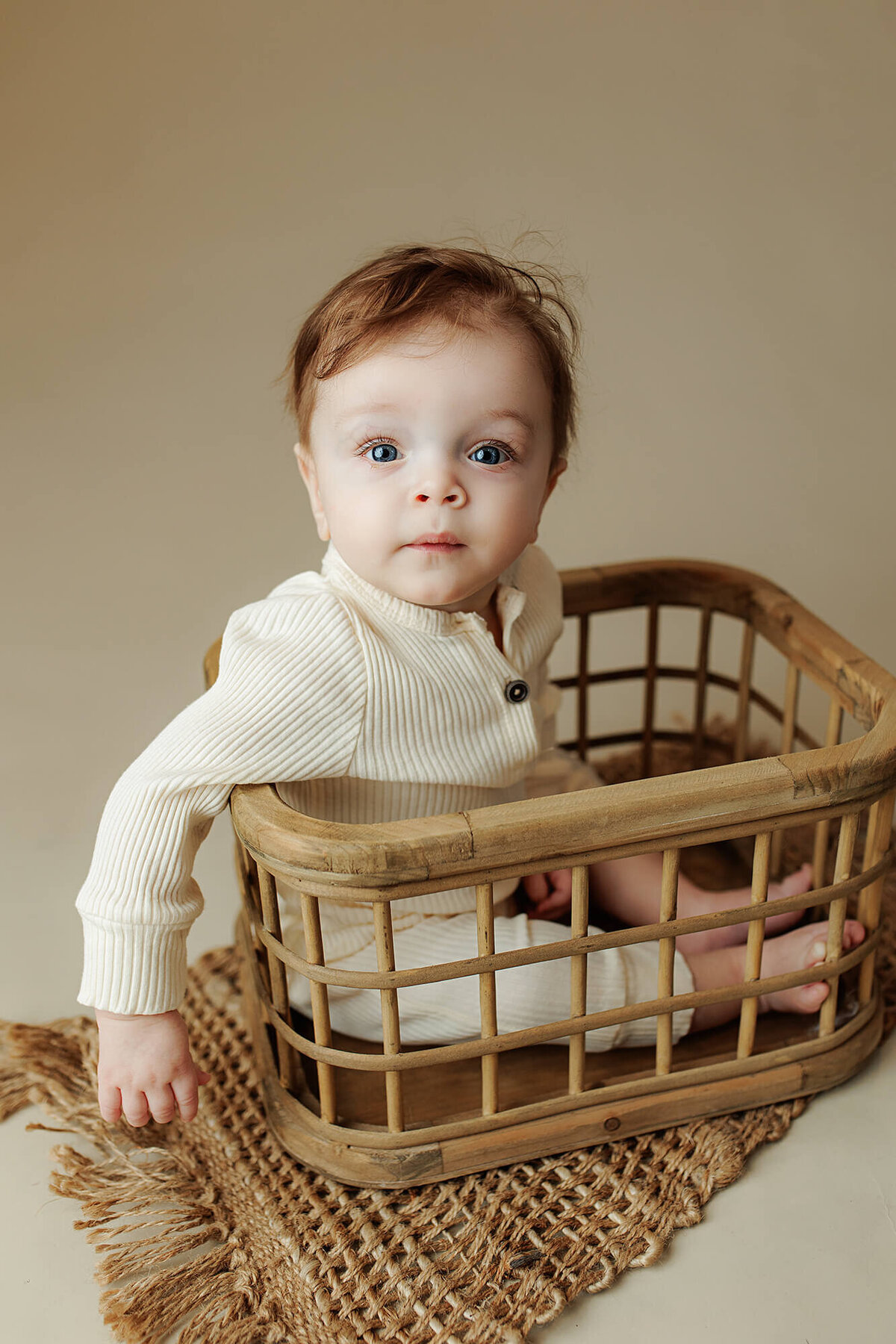 Baby boy in a bamboo crate during his milestone session at Jennifer Brandes Photography.