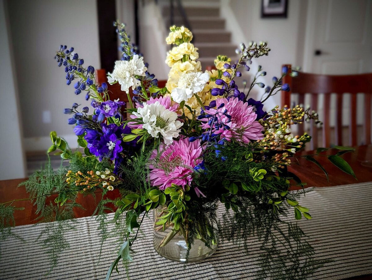 white funeral flowers with purple and yellow in vase