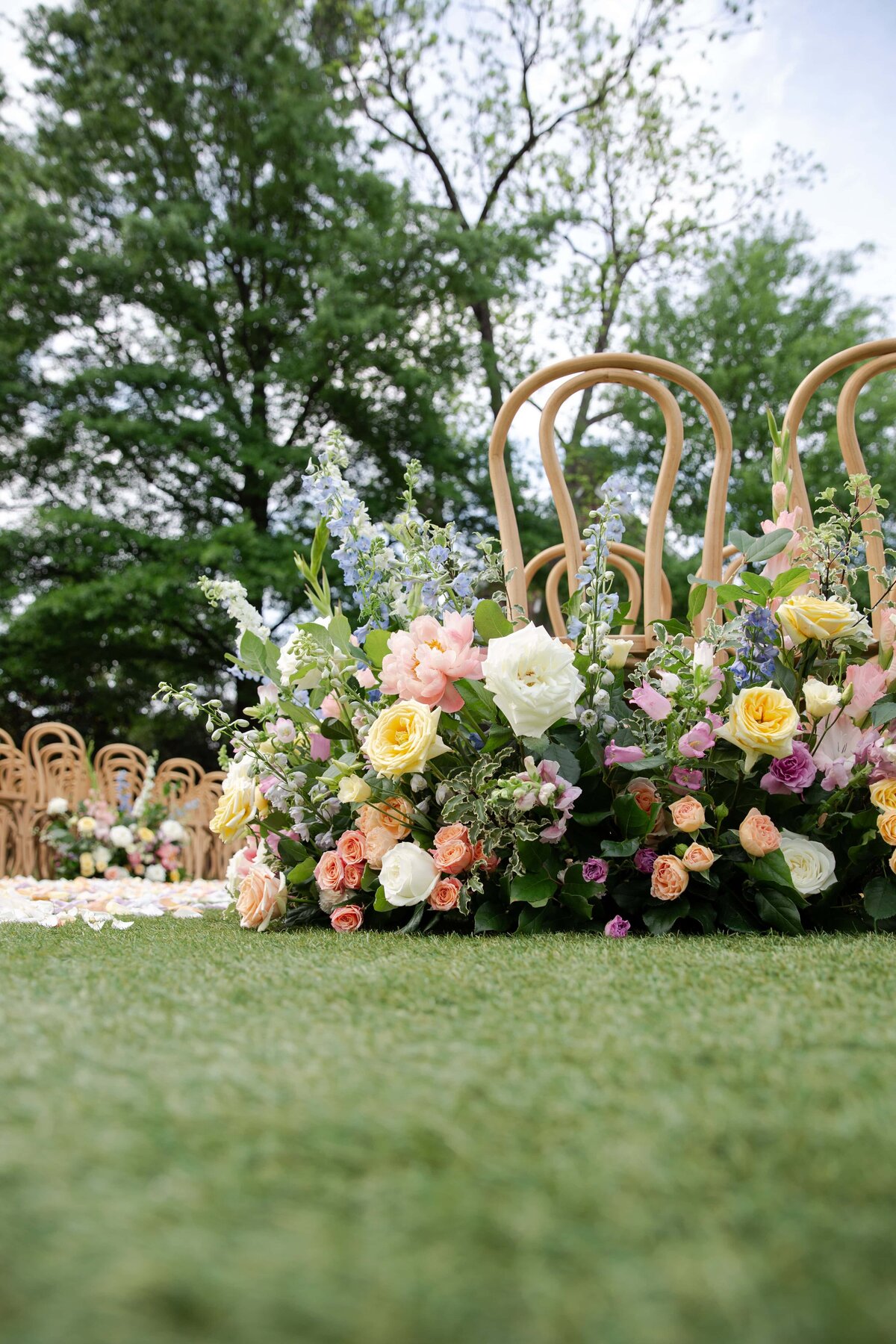 Wedding ceremony setup with colorful spring floral arrangement on the lawn of Merrimon-Wynne House