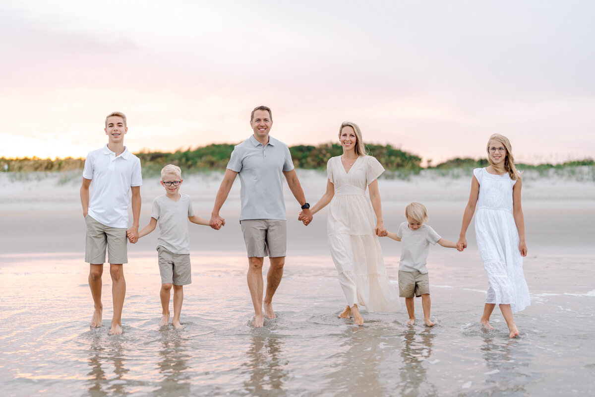 During a family photo shoot in South Carolina, the family held hands and walked on the beach at sunset in Myrtle Beach.