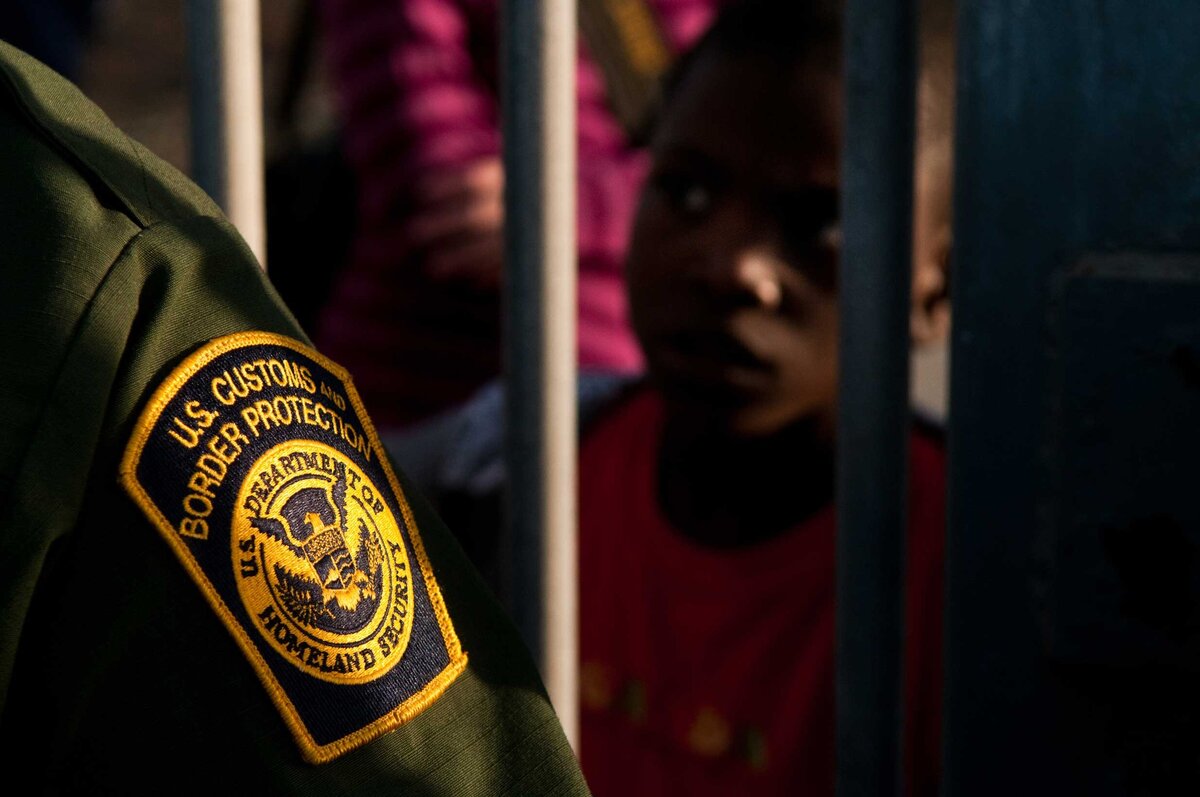 A child peers at a border patrol office at Friendship park. Officer;s badge is in the foreground.