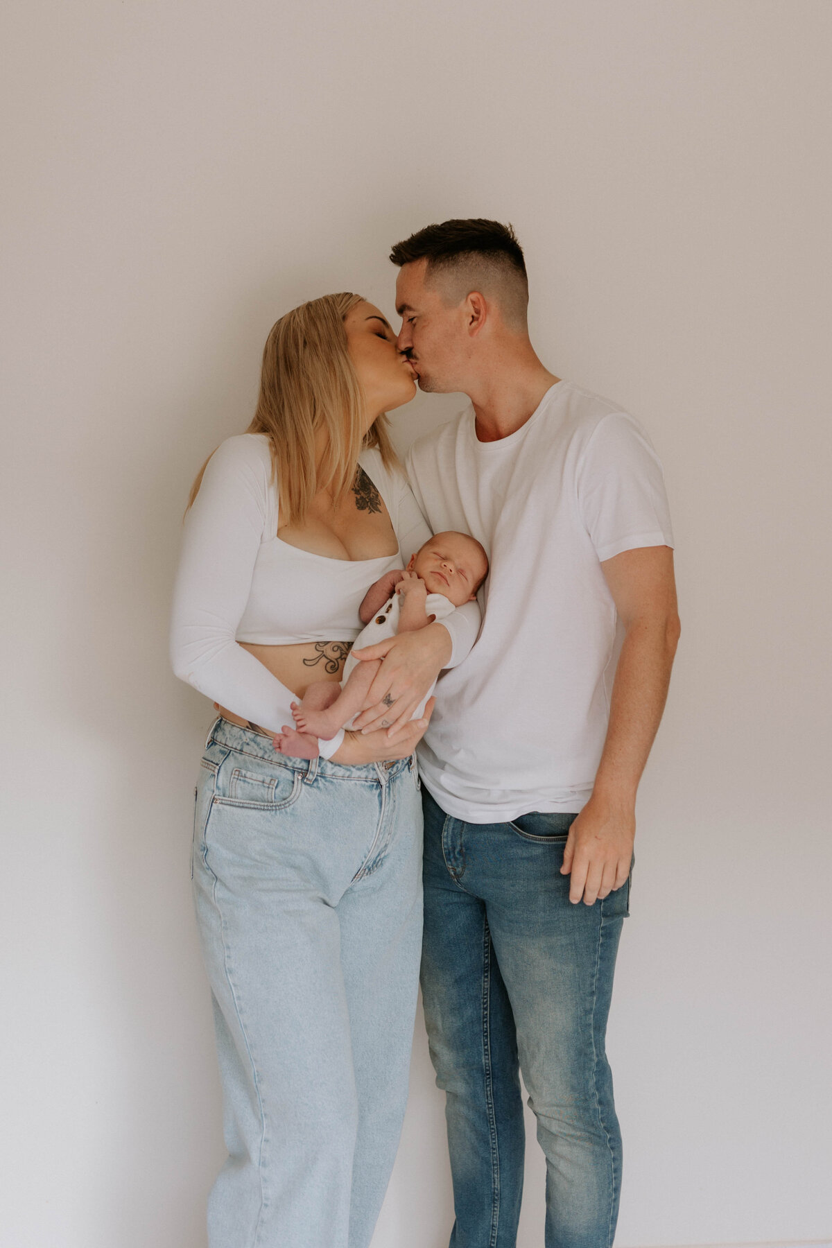 Mother and Father kissing with newborn baby in arms