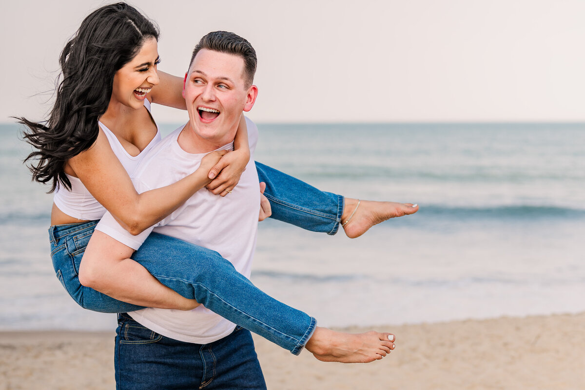 Playful beach fun of an engaged couple on Wrightsville beach at sunset enjoying their Wilmington wedding photos