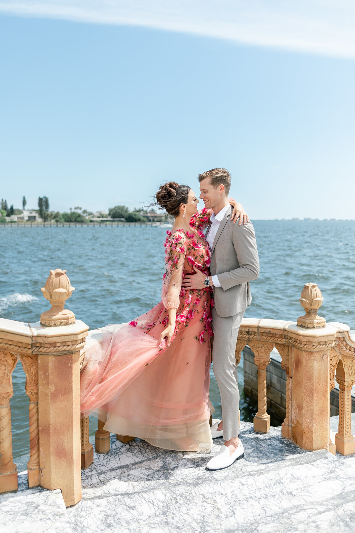 couple smiling at each other in front of the ocean by wedding photographer in sarasota