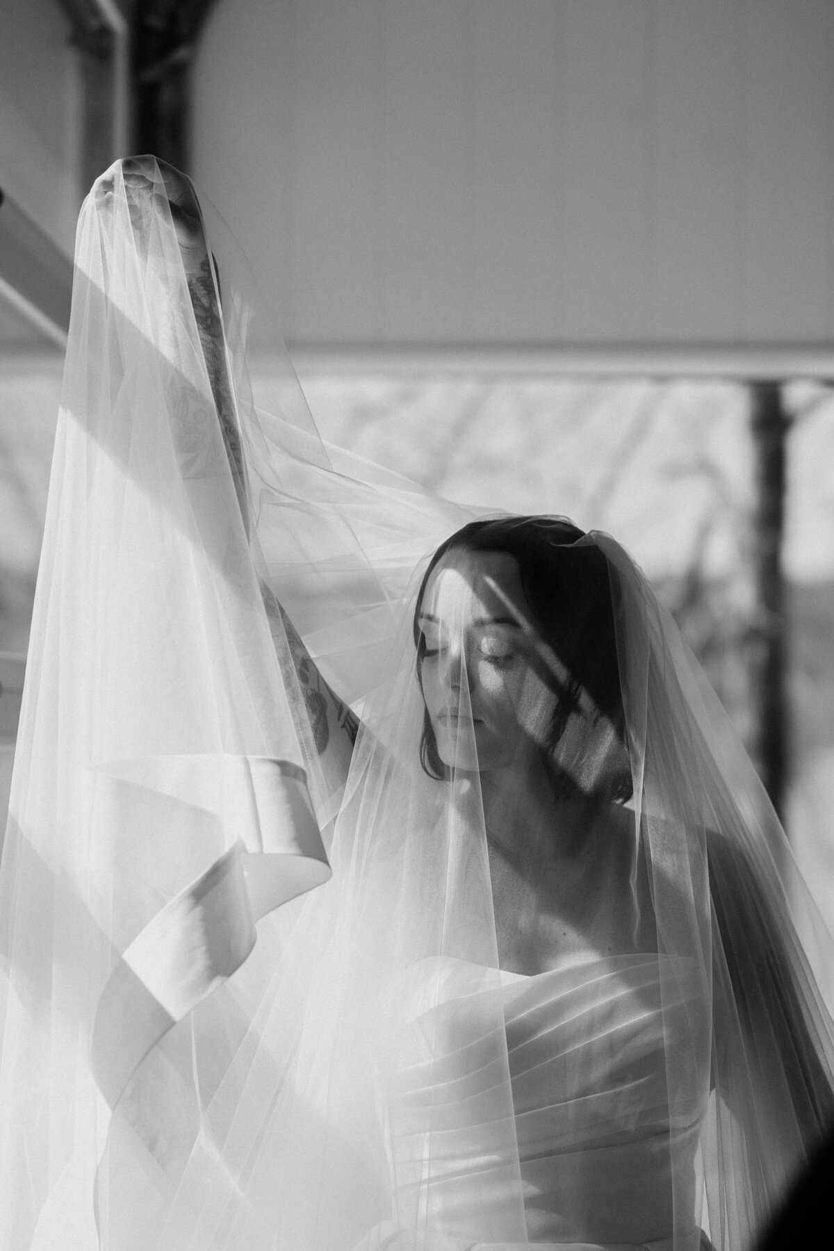 A bride posing with her veil in black and white