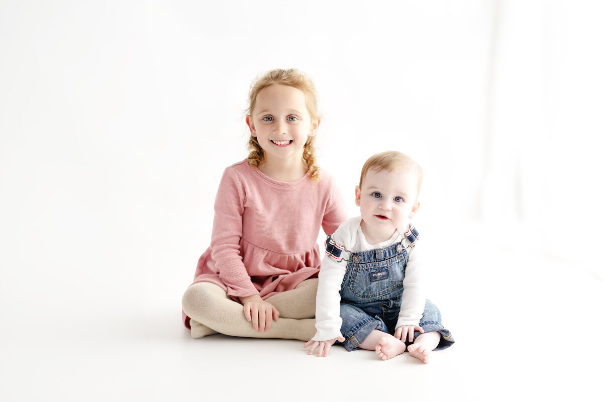 Sibling and baby portrait in a white studio setting—capturing the joy and warmth of family during a milestone session in Paris, Ontario.