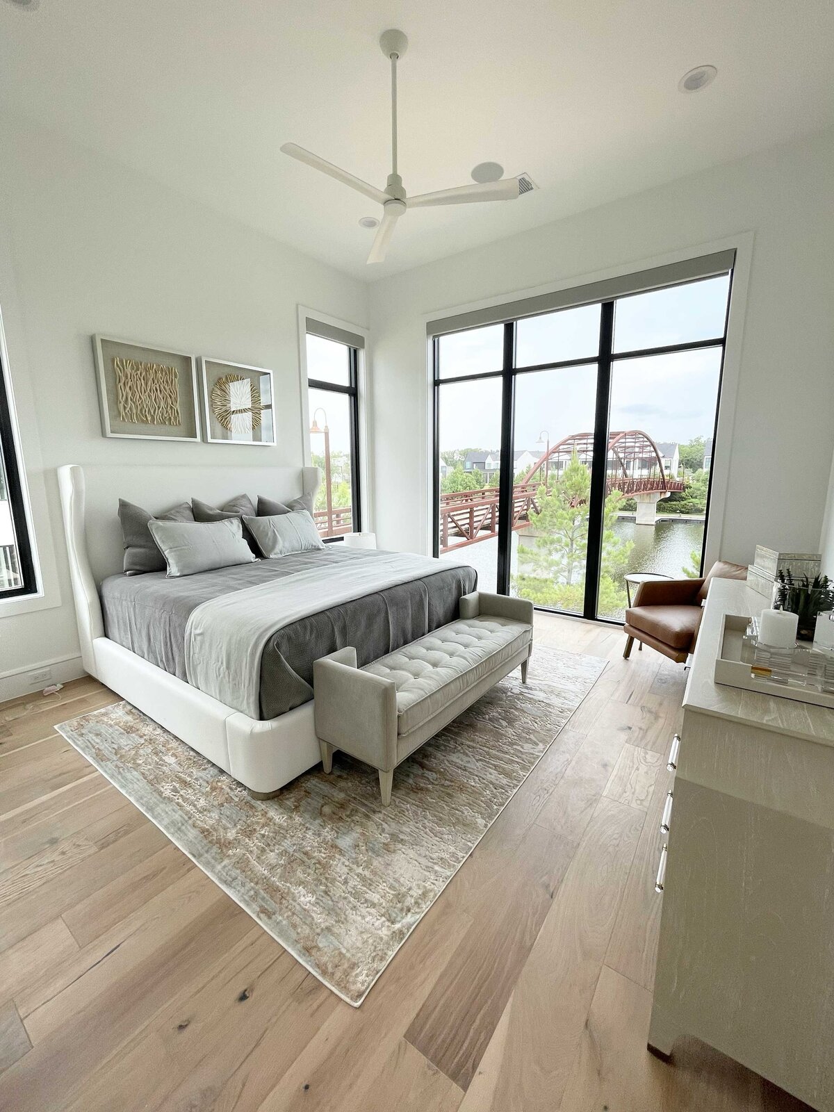 Professional home styling service for a bedroom featuring grey and white decorations. The atmosphere is enhanced with two artworks, a TV table, and elegant lamps for a sophisticated touch.