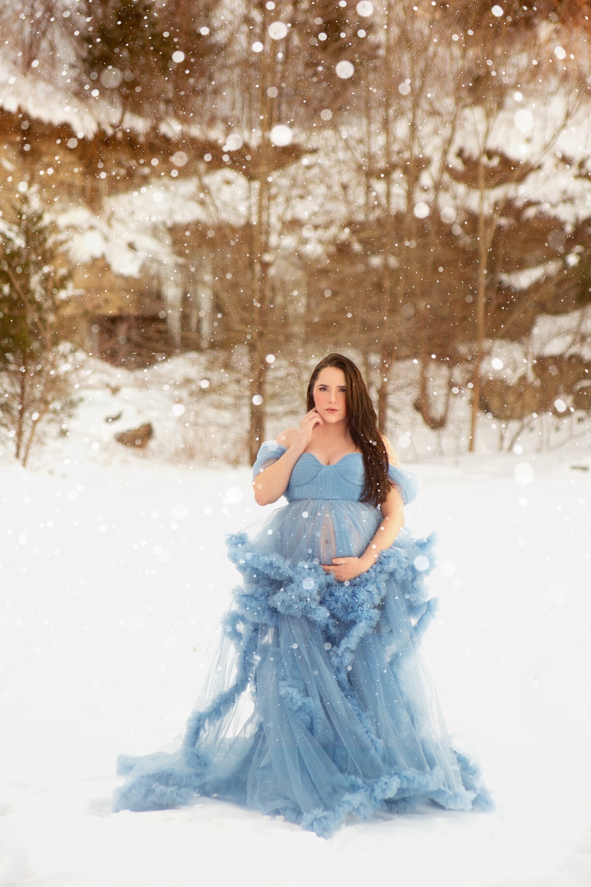 Woment wearing blue glam gown in the snow during maternity photoshoot in Mount Juliet Tennessee