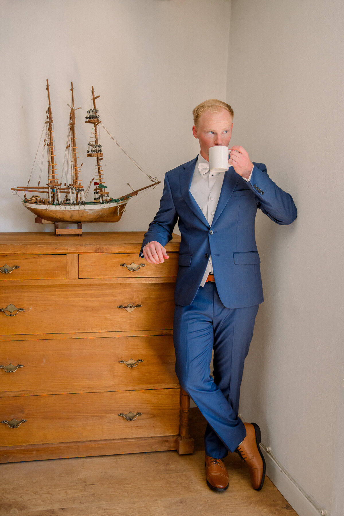 Destination Wedding in Spain | Groom in blue suit and brown dress shoes sips his morning coffee before leaving for his church wedding ceremony in Spain.