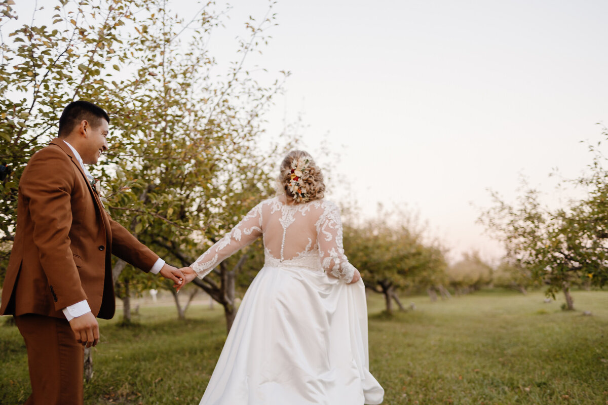 A person holding their partner's hand as they walk through a vineyard