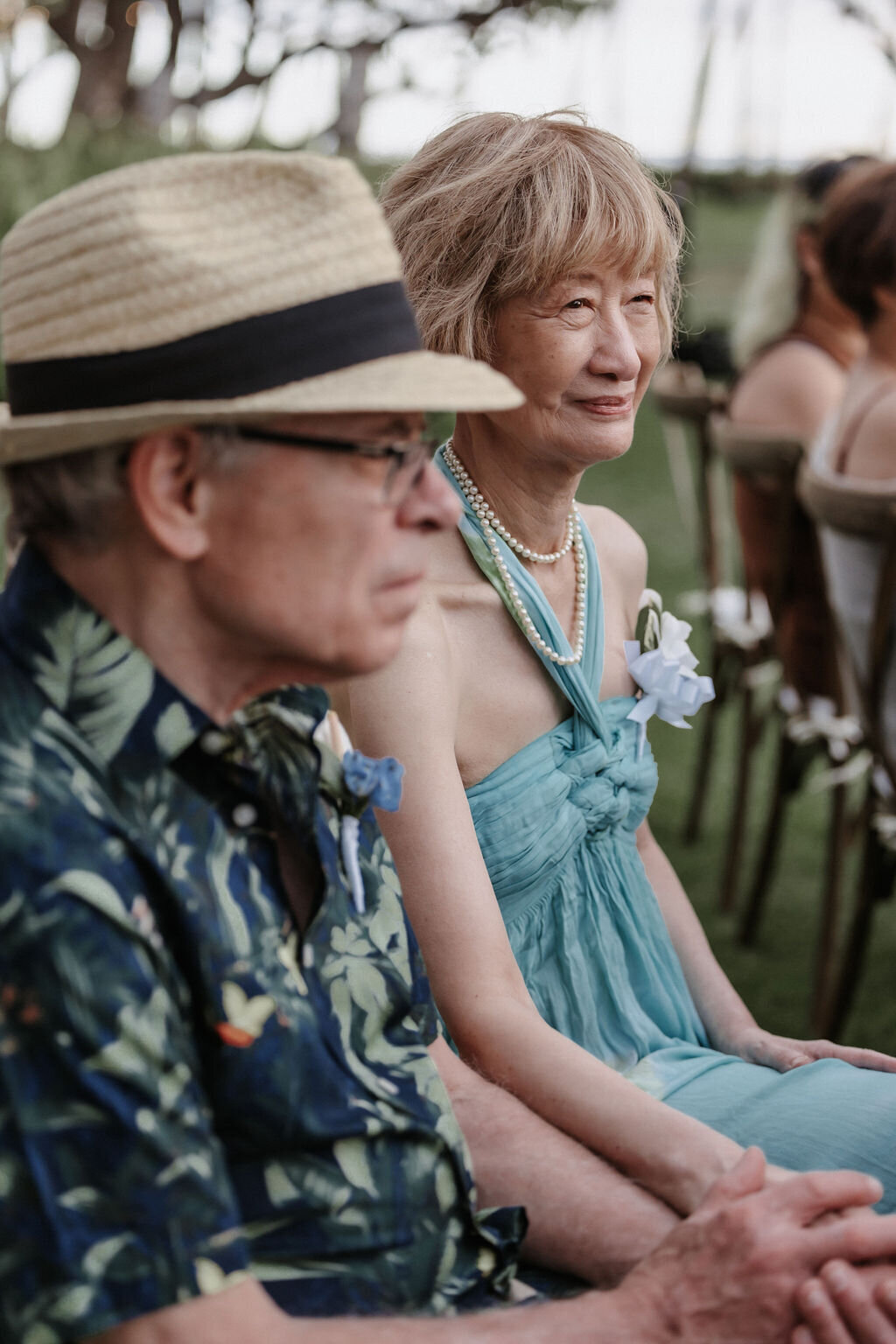 Couple seated at wedding ceremony at lanikuhonua holding hands