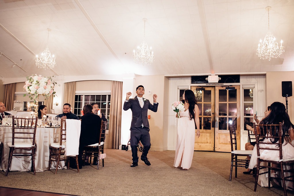 Wedding Photograph Of Groomsman Raising His Hands And Bridesmaid Carrying a Bouquet Los Angeles