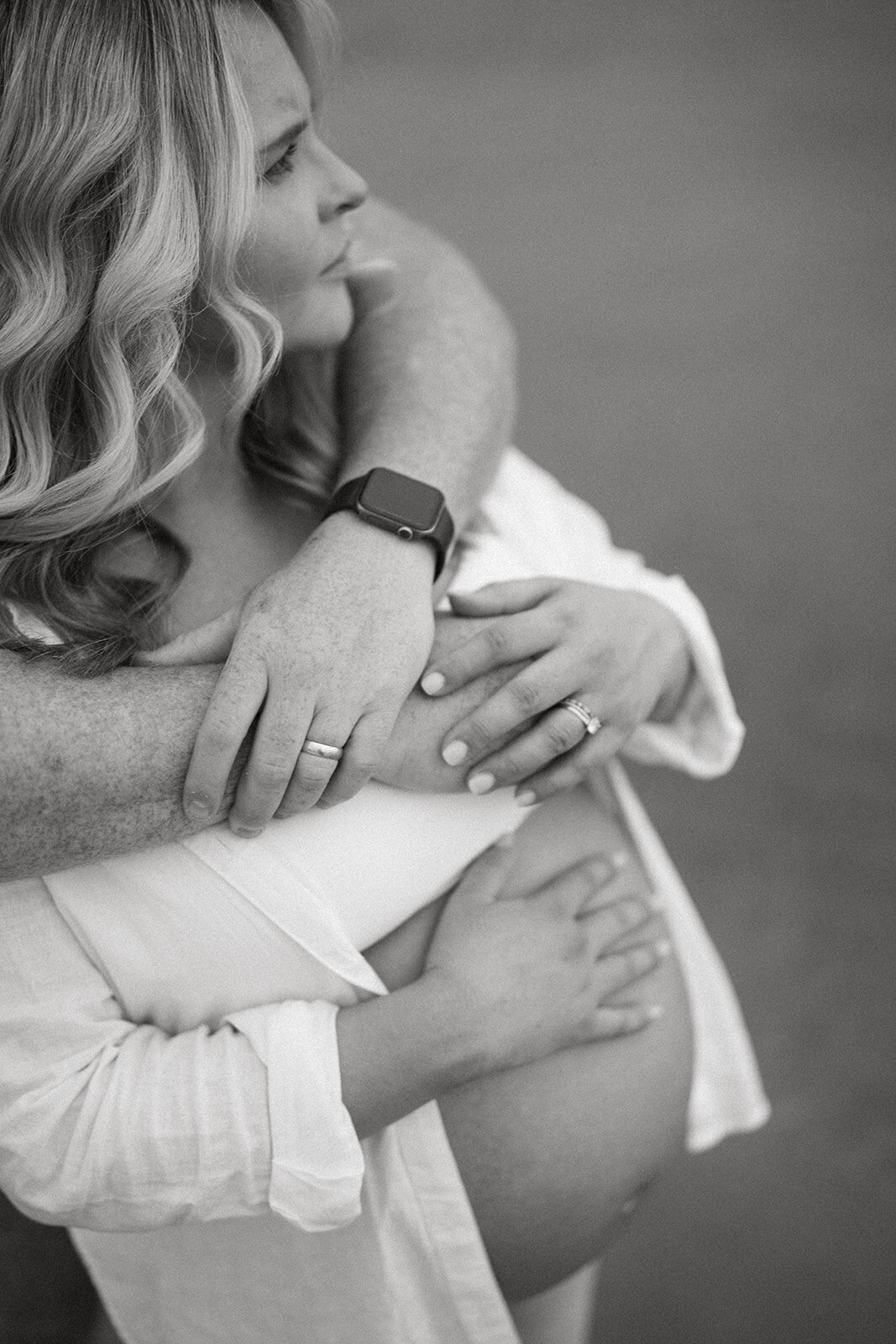 Expecting father hugging pregnant mother from behind during sunset maternity photos at South Haven North Beach.