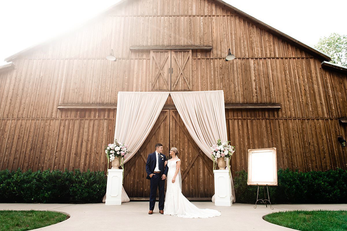 Bride and groom standing in front of Saddlewood Farm barn