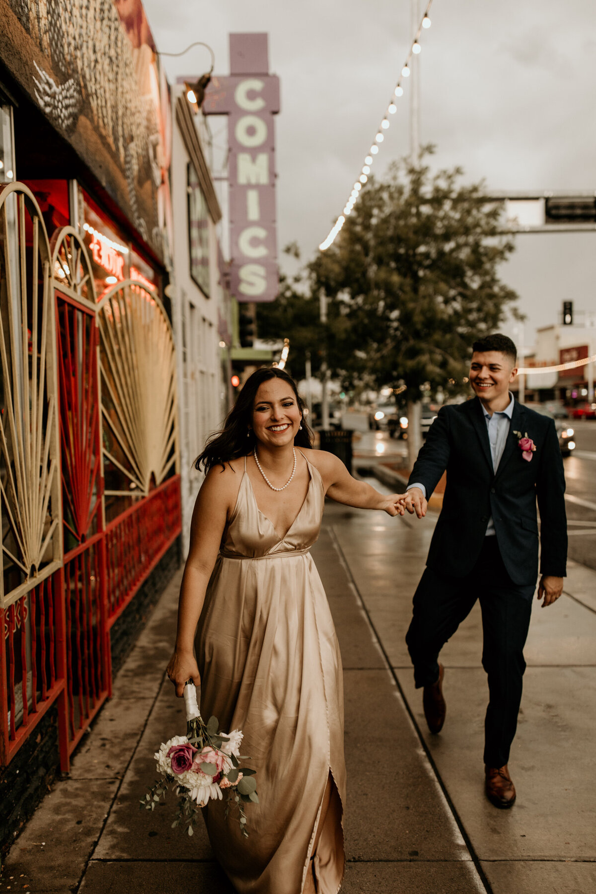 newlyweds walking down Central Ave in the rain in downtown Albuquerque