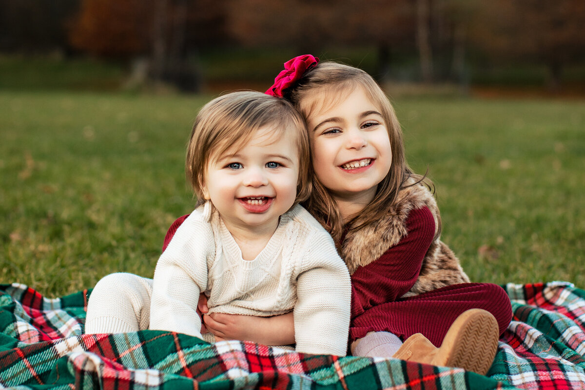 Brothers and sisters smile and embrace in a witted field during a fall family mini session with larger than life photography