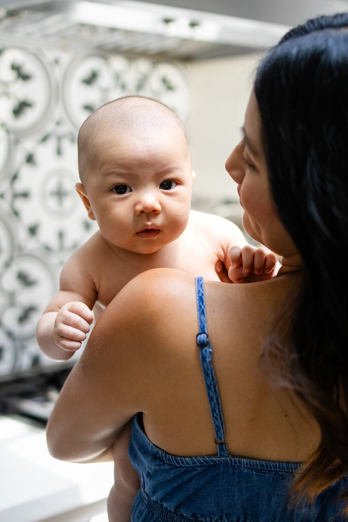 Peaceful scene of mother swaddling newborn by window light, documented by San Francisco newborn photographer.
