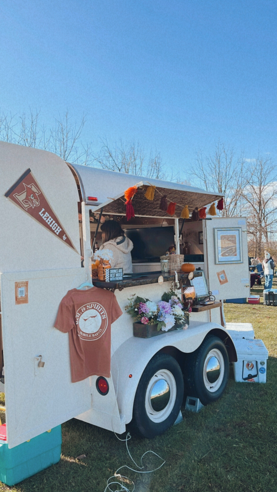 Trailer with flowers, t shirt, and other decor hanging on it at event outside