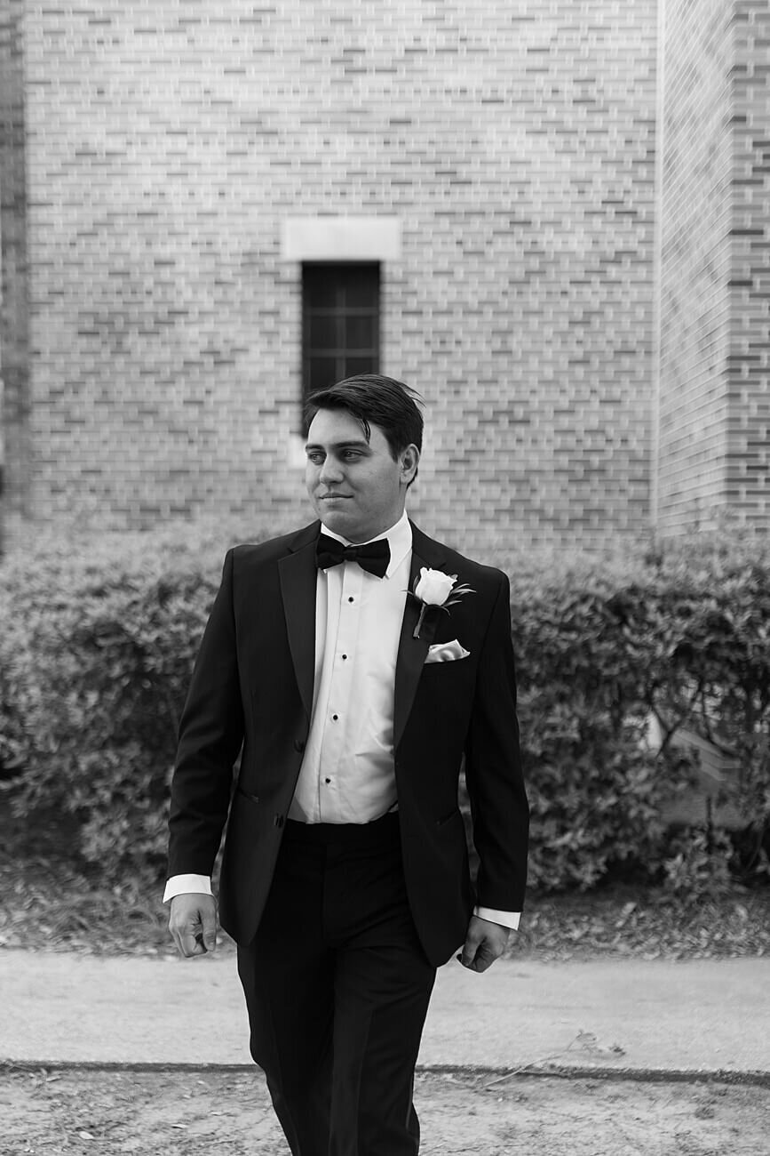 groom walking in front of brick wall