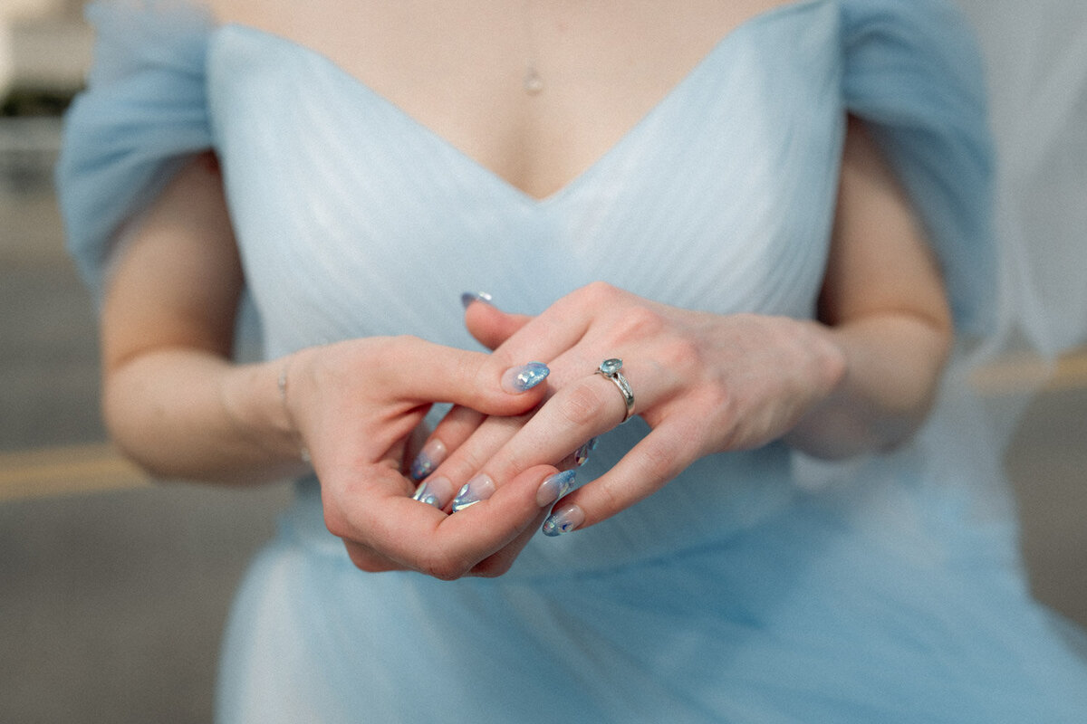 Bride shows her blue ring with blue nails and blue dress