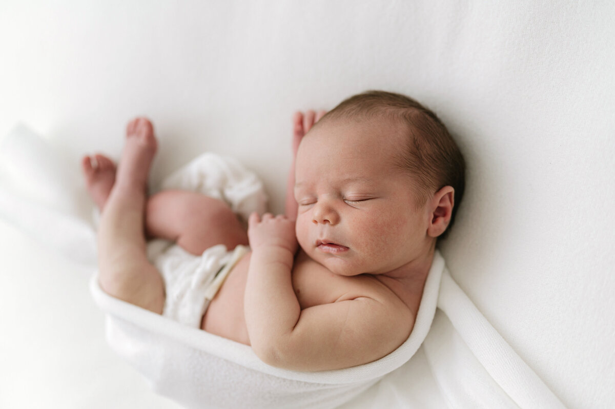 Artistic photography of a baby asleep in a white blanket