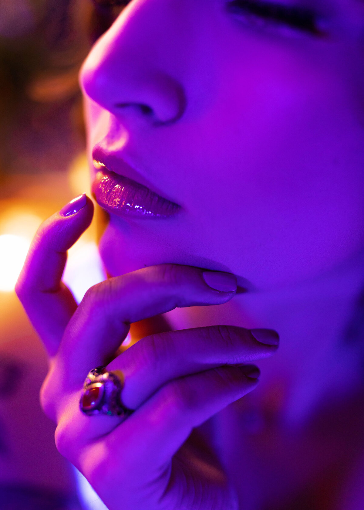 close up boudoir portrait of woman in blacklight lighting with hands on face