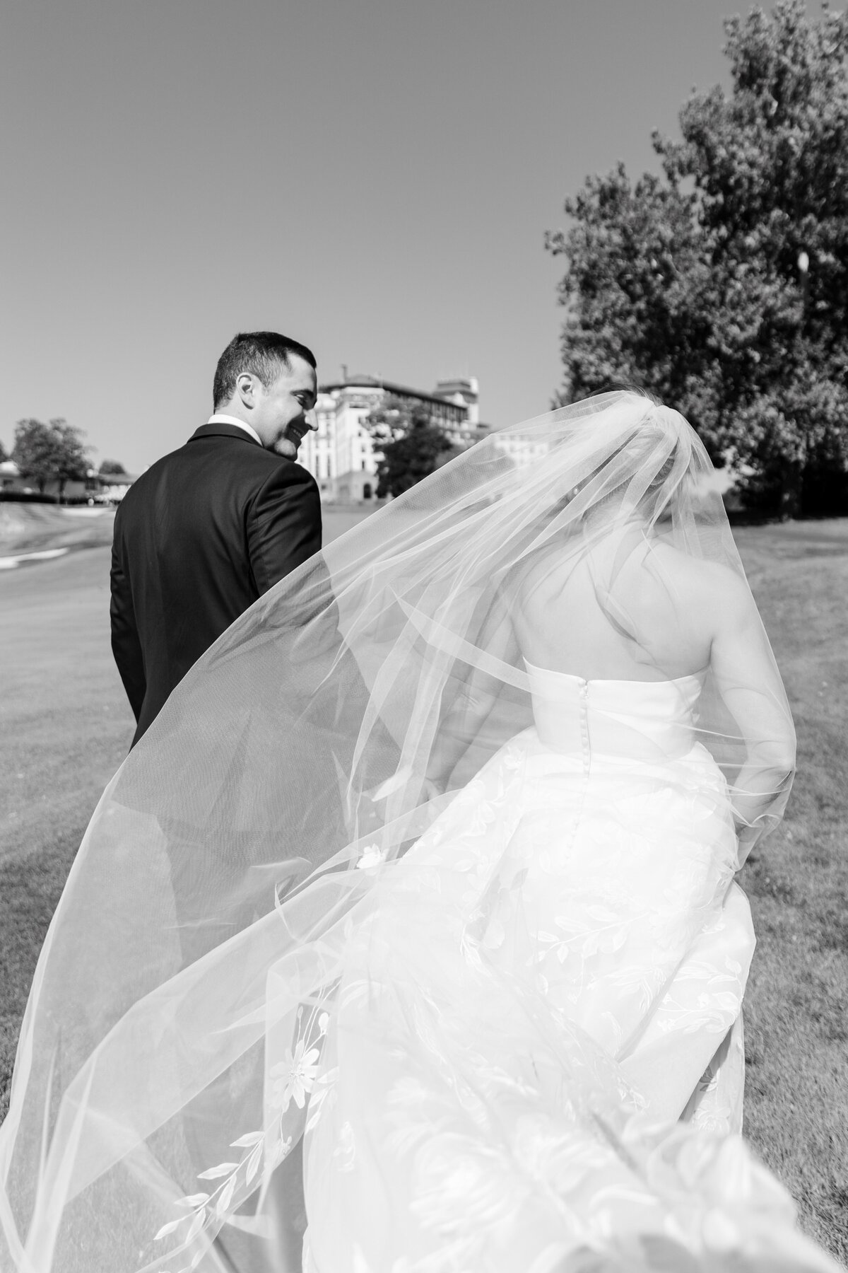 groom walking with bride while wind is blowing through her veil