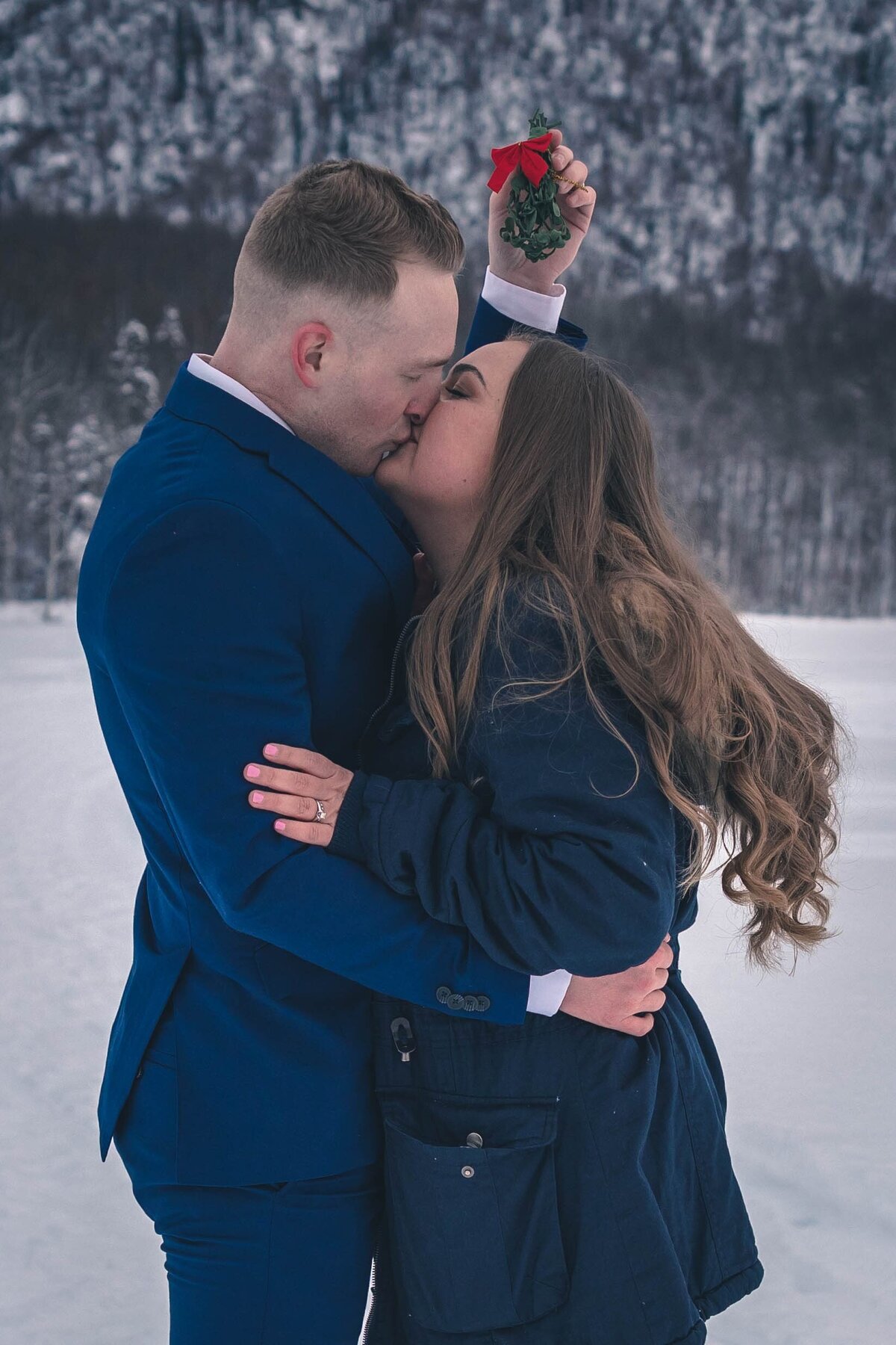 A military couple kisses below the mistletoe on their christmas wedding