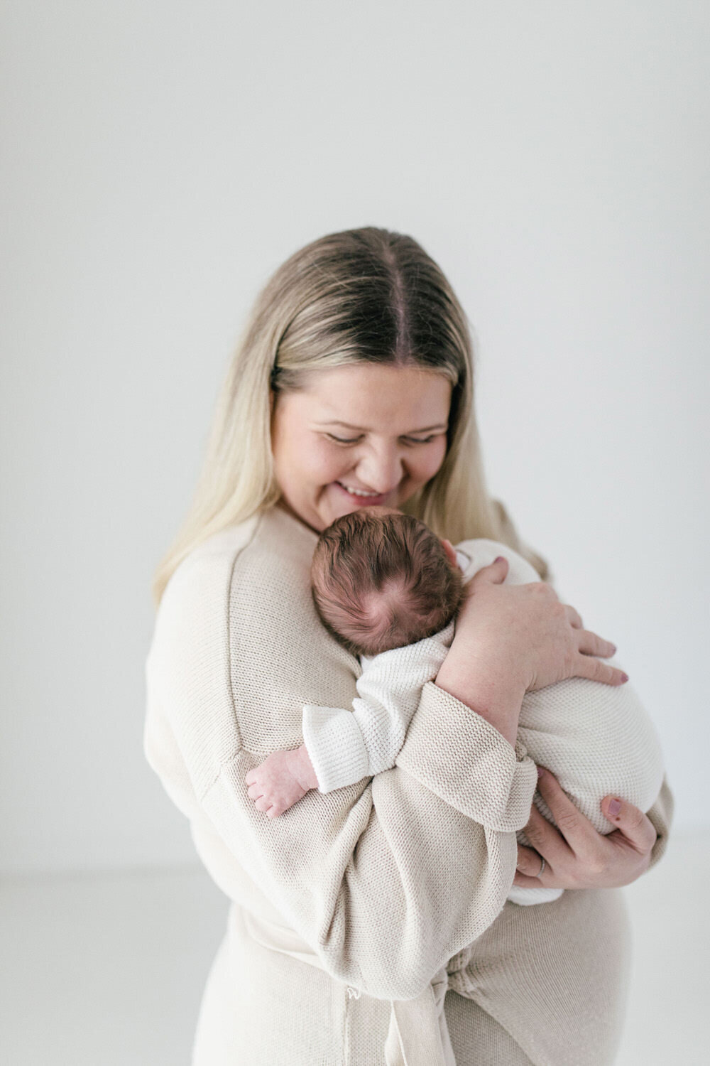 mum holds newborn baby whilst smiling at them