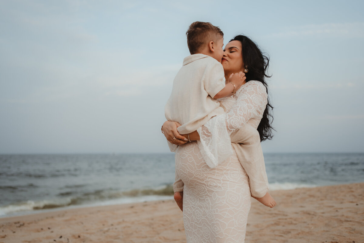 Expectant mother holding her toddler son during a maternity session on the beach in Pennsylvania