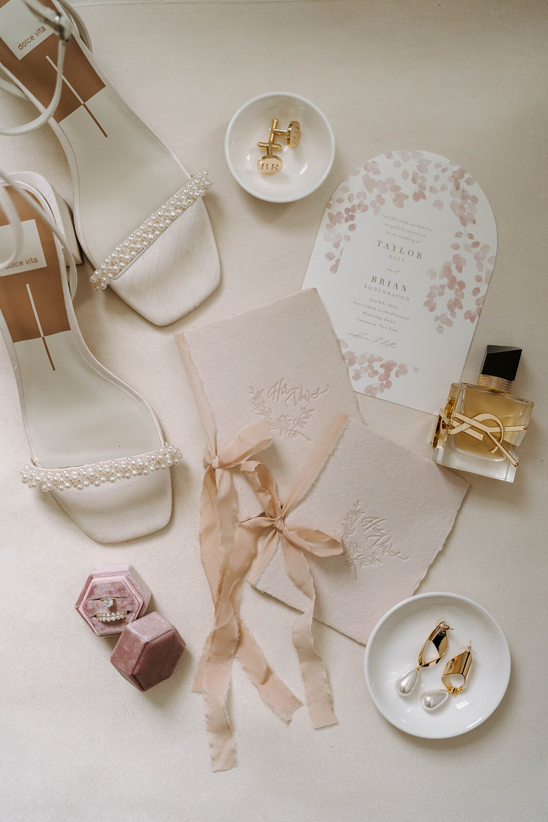 wedding bridal details flatlay photo with heels, ysl perfume, vow book, and jewelry