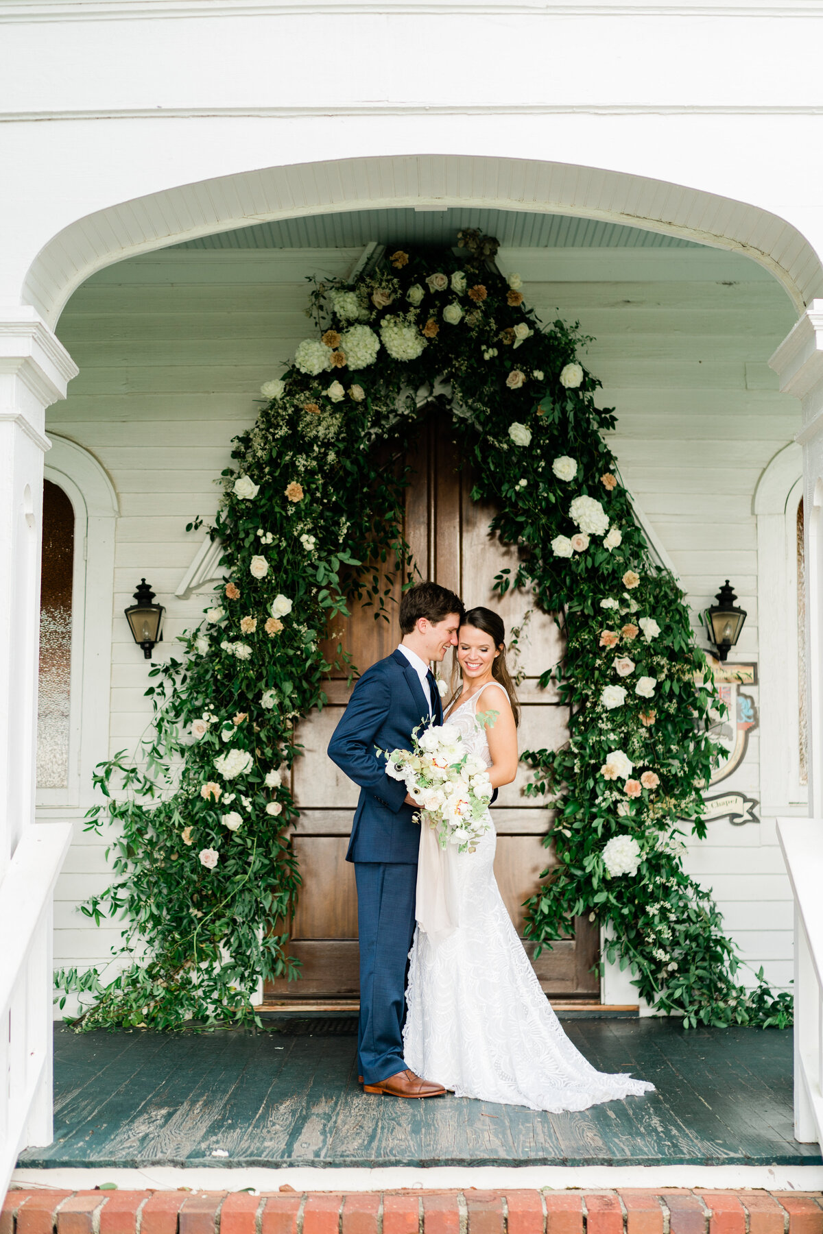 Bride and groom under archway made with greenery
