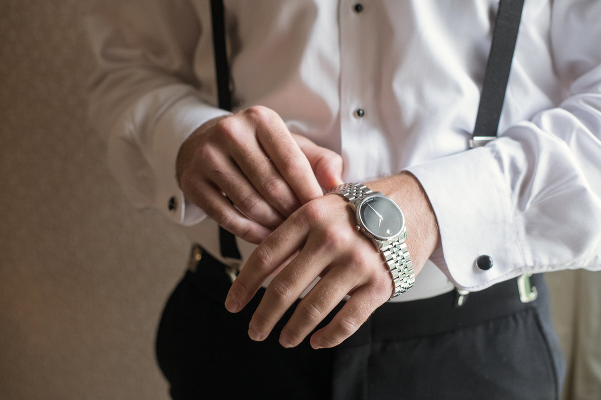 groom putting his watch on for wedding at The Muttontown Club