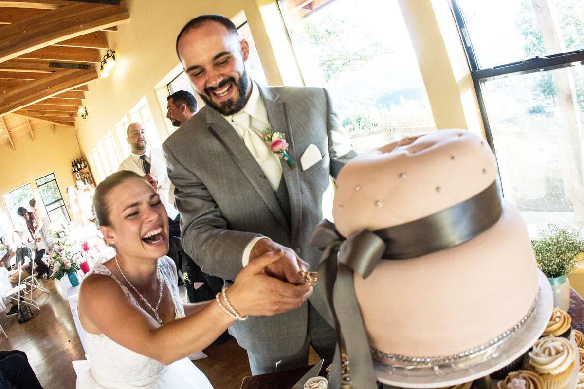 bride and groom laughing cutting cake