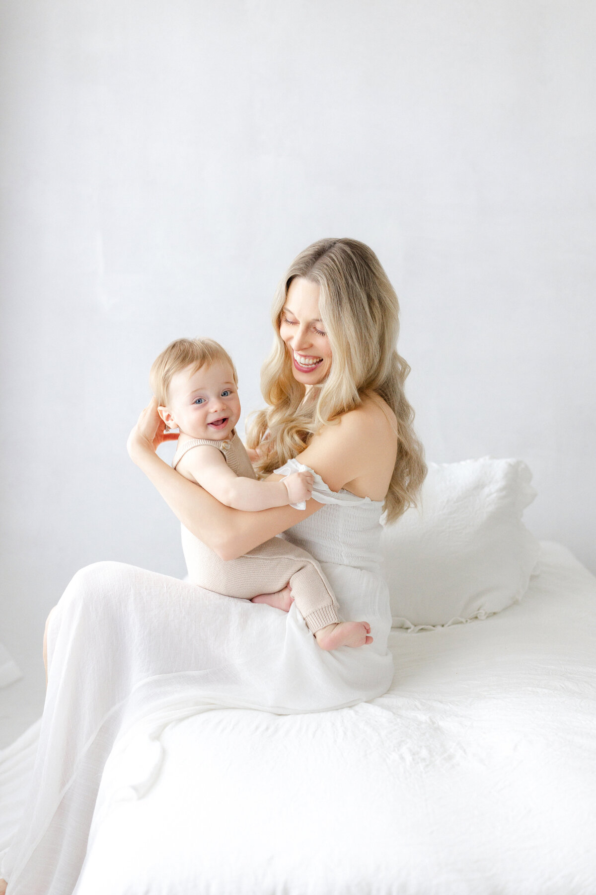 Tampa 6-month milestone portrait of smiling baby boy and mother in natural light studio