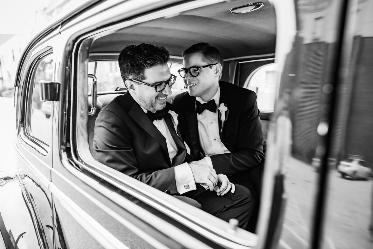 LGBTQ couple shares a romantic candid moment in an old car at their Chicago wedding