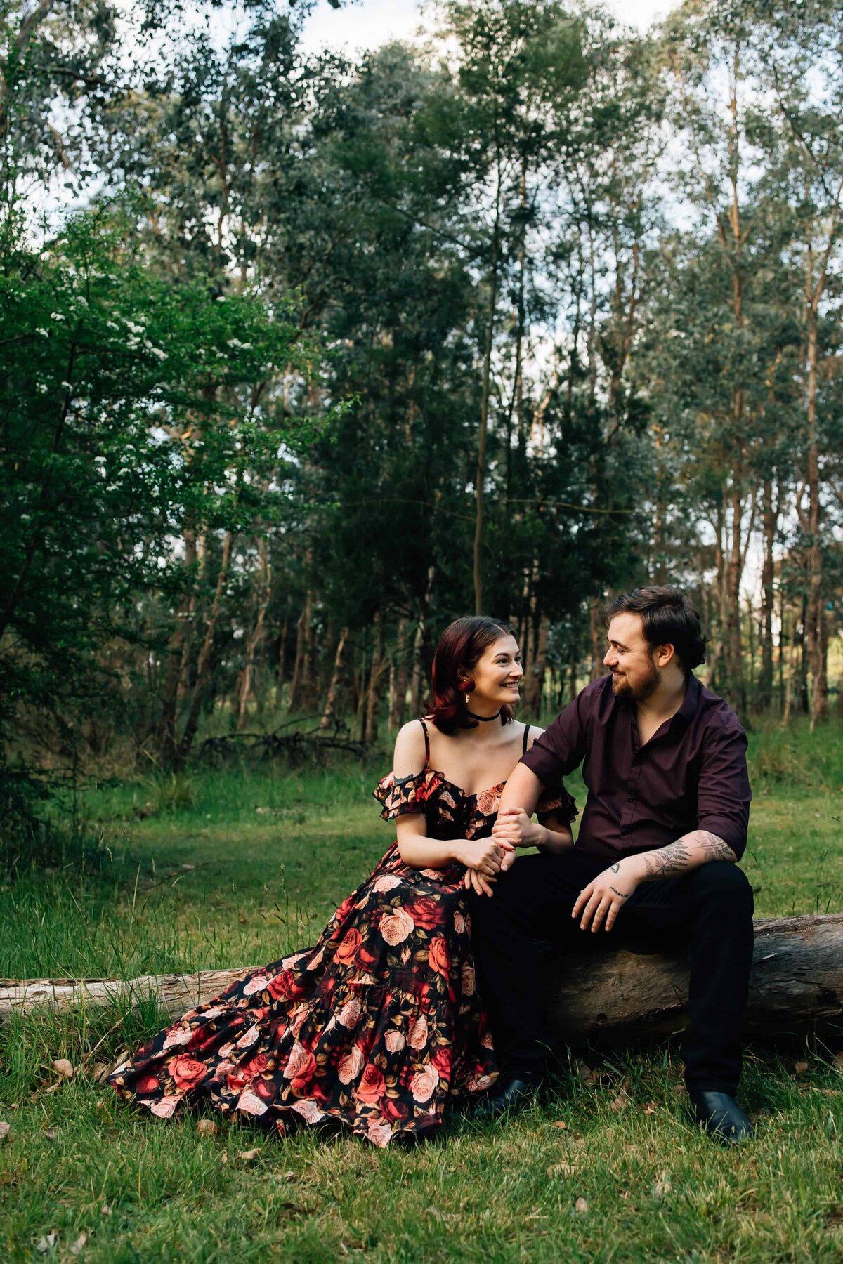 Couple sitting on a log looking at each other, during outdoor couples photoshoot Melbourne by And So I Don't Forget Photography