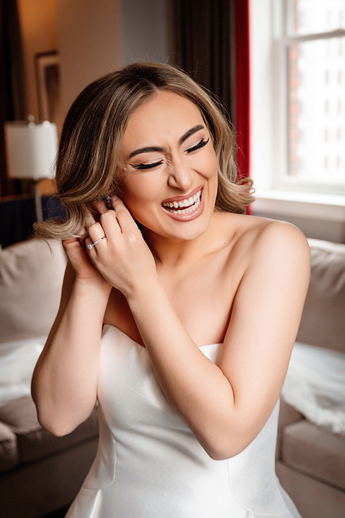 bride smiling as she puts on earrings at duquesne club suite
