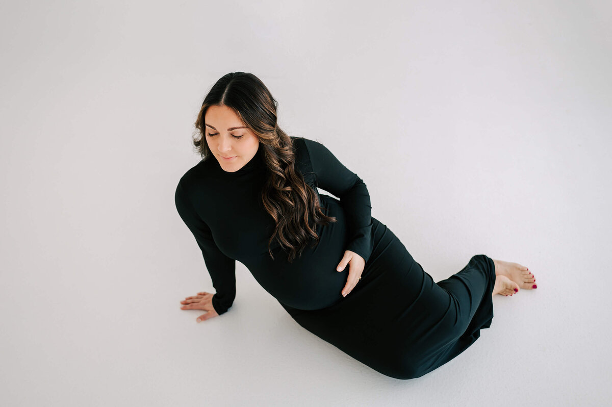 Joplin Mo materniy photographer captures pregnant mom holding baby bump sitting on floor