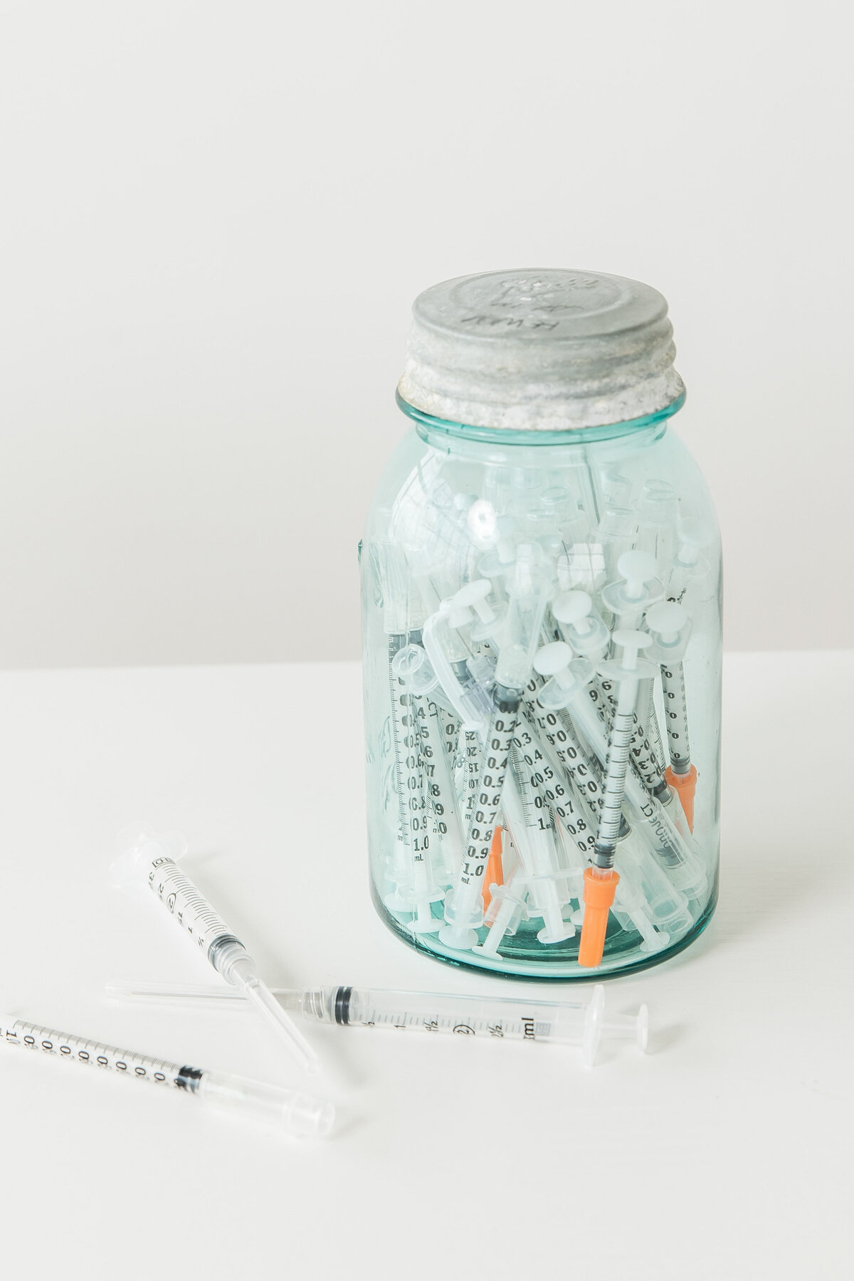 a glass jar with syringes