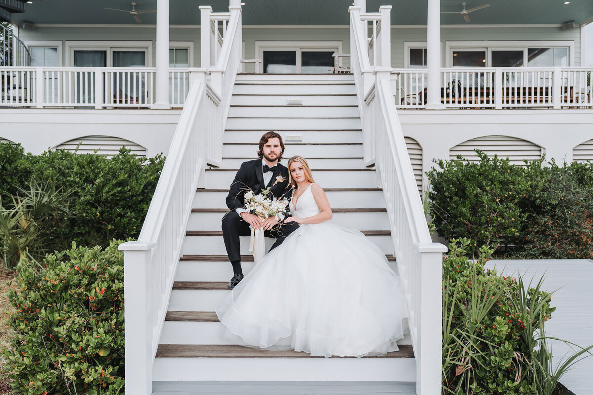 Bride leans on grooms arm as they sit on stairs
