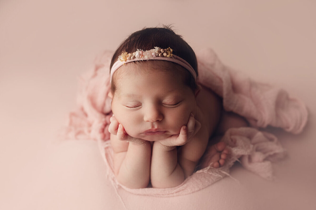 baby girl sleeping in froggy pose on pink drop
