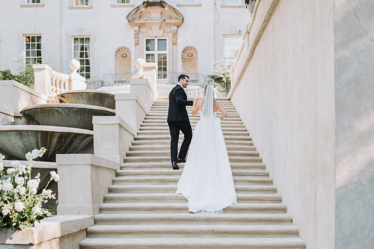 bride and groom walk up stairs of swan house wedding venue