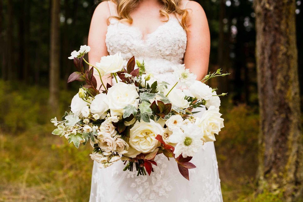 Bridal bouquet of white and champagne fall flowers mixed with fall foliage